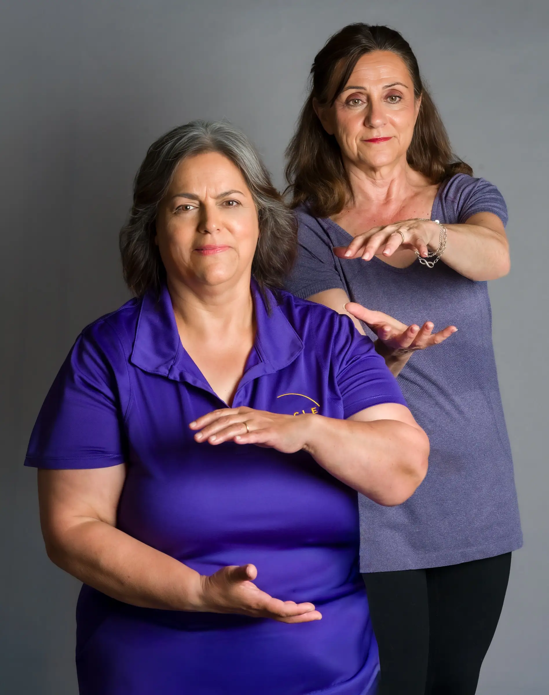 Esmeralda Reynolds and a fellow practitioner in a holding-ball tai chi pose in the studio
